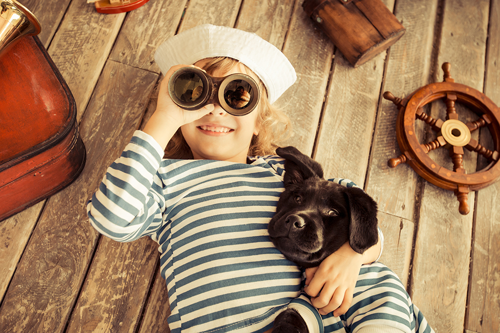 Child using binoculars hugging dog